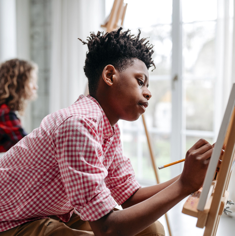 Teen at easel painting with a brush